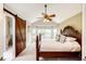 This main bedroom features a vaulted ceiling, ceiling fan and ensuite bathroom access through a rustic sliding barn door at 9846 Spring Hill Ln, Highlands Ranch, CO 80129