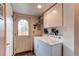 Bright laundry room with cabinets, white washer, dryer, and exterior access at 10154 W Hawaii Pl, Lakewood, CO 80232