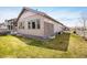 View of the grassy backyard featuring stone accents on this home's exterior at 16392 Spanish Peak Way, Broomfield, CO 80023