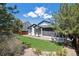 Well-maintained backyard featuring green grass, a stone border, and mature trees at 1488 Baguette Dr, Castle Rock, CO 80108