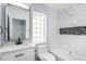 Updated bathroom featuring a modern vanity, glass block window, and tub with white tile at 1963 Hogan Ct, Castle Rock, CO 80109