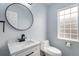 Stylish half-bath with modern vanity, round mirror, and decorative glass block window at 1963 Hogan Ct, Castle Rock, CO 80109