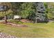 Lush front yard featuring mature trees, retaining walls, decorative rock, and a well-maintained lawn at 5506 Irish Pat Murphy Dr, Parker, CO 80134