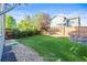 A well maintained lawn with mature trees is surrounded by a wood fence at 1464 Spotted Owl Way, Highlands Ranch, CO 80129