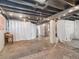 Finished basement with concrete floor and ceiling, decorated with curtains and furniture at 6940 W 48Th Ave, Wheat Ridge, CO 80033