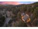 Aerial shot of a house surrounded by mature trees and a paved driveway during twilight at 29089 Western Ln, Evergreen, CO 80439