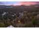 Scenic aerial view showcases the house nestled among a dense forest landscape against a stunning sunset at 29089 Western Ln, Evergreen, CO 80439