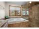 Bathroom featuring a jacuzzi tub, walk-in shower, and a window providing natural light at 29089 Western Ln, Evergreen, CO 80439