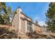 Side view of a house showing the light colored siding, roof, and surrounding trees on a sunny day at 29089 Western Ln, Evergreen, CO 80439