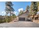 View of home with garage and driveway surrounded by trees and natural landscaping at 29089 Western Ln, Evergreen, CO 80439