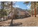 View of the home's exterior with wooden deck on a sloped lot surrounded by tall trees at 29089 Western Ln, Evergreen, CO 80439