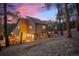 Exterior shot of a home featuring a well-maintained backyard and warm interior lighting at dusk at 29089 Western Ln, Evergreen, CO 80439