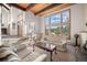 Living room with wood-beamed ceiling, stone fireplace, and large windows providing natural light at 29089 Western Ln, Evergreen, CO 80439