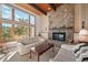 Bright living room featuring a stone fireplace, wood-beamed ceilings, and large windows at 29089 Western Ln, Evergreen, CO 80439