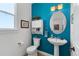 Charming powder room featuring a pedestal sink, decorative mirror, and bright blue accent wall at 5372 Lenox Ct, Castle Rock, CO 80104