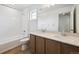 Bathroom featuring double sinks, a wide mirror, wood cabinets, and shower with tub at 24717 E 40Th Ave, Aurora, CO 80019