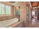 Elegant bathroom boasting a soaking tub, glass shower, and travertine tile throughout for a spa-like experience at 6638 S Tibet Ct, Aurora, CO 80016