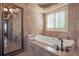 Elegant bathroom featuring a soaking tub, a rain-style faucet, and travertine tile throughout for a spa-like experience at 6638 S Tibet Ct, Aurora, CO 80016