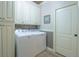 Bright laundry room features a washer and dryer, upper storage cabinets, and decorative backsplash at 6638 S Tibet Ct, Aurora, CO 80016