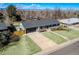 Inviting home features a spacious driveway, lush green lawn, attached garage, and meticulously maintained front yard landscaping at 3461 S Ivy Way, Denver, CO 80222