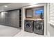 Well-organized laundry room featuring gray cabinets, shelving, and modern washer and dryer at 3461 S Ivy Way, Denver, CO 80222