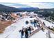 Scenic aerial view of a snow-covered neighborhood nestled in a mountain landscape with mature trees and a winding road at 9019 Armadillo Trl, Evergreen, CO 80439