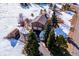 Aerial view of a two-story house featuring a two-car garage, deck, storage shed, and mature trees in winter at 9019 Armadillo Trl, Evergreen, CO 80439