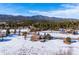 Aerial view of a snow-covered home with mountain views, surrounded by mature trees on a sunny day at 9019 Armadillo Trl, Evergreen, CO 80439