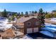 Charming two-story home with a two-car garage and deck, surrounded by trees and snow at 9019 Armadillo Trl, Evergreen, CO 80439