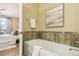 Modern bathtub with stone tile accent and view to the bedroom at 5438 Valentia St, Denver, CO 80238