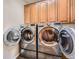 Modern laundry room featuring front-load washer and dryer and wooden cabinets for storage at 11839 E Maplewood Ave, Greenwood Village, CO 80111