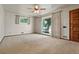 Bright living room features neutral carpet, white walls, large window, ceiling fan, and a wooden front door at 1803 Graves Ct, Northglenn, CO 80233