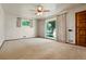 Bright living room features neutral carpet, white walls, large window, ceiling fan, and a wooden front door at 1803 Graves Ct, Northglenn, CO 80233