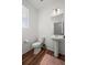 Small full bathroom with wood floors, a toilet, vanity, pedestal sink and a window for natural light at 10909 Memphis Ct, Commerce City, CO 80022