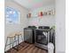 Convenient laundry room equipped with modern washer and dryer, shelving, and a window, and two stools at 10909 Memphis Ct, Commerce City, CO 80022