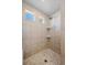 Tiled shower with mosaic floor, corner shelves, natural light, and a showerhead at 10909 Memphis Ct, Commerce City, CO 80022