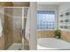 Modern bathroom featuring walk-in shower with glass door, soaking tub, and frosted glass-block window at 3733 S Perth Cir # 101, Aurora, CO 80013