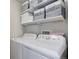 Bright laundry room with front-loading washer and dryer, white shelves, and gray storage boxes at 3733 S Perth Cir # 101, Aurora, CO 80013