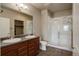 Bathroom features double sinks, framed mirror, walk-in shower with glass door, and vinyl flooring at 12444 Madison Way, Thornton, CO 80241