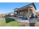 Landscaped backyard with a covered patio, artificial grass, and a stone patio at 8259 Arapahoe Peak St, Littleton, CO 80125