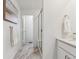 A narrow bathroom with marble floors, glass enclosed shower, a doorway and a painting at 645 Flintwood Pl, Lafayette, CO 80026