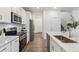 Modern kitchen with white cabinetry, stainless steel appliances, and a quartz countertop island with a sink at 645 Flintwood Pl, Lafayette, CO 80026