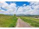Scenic neighborhood trail with views of green meadows and mountain range under a bright blue, cloudy sky at 645 Flintwood Pl, Lafayette, CO 80026