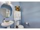 Charming powder room featuring a pedestal sink, decorative mirror, and a soothing blue color scheme at 16352 E 104Th Way, Commerce City, CO 80022
