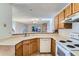 Well-lit kitchen with light wood cabinets and appliances, overlooking the living room and stone fireplace at 7476 E Arkansas Ave # 35-10, Denver, CO 80231
