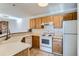 Functional kitchen featuring wood cabinetry, white appliances, and a convenient breakfast bar area at 7476 E Arkansas Ave # 35-10, Denver, CO 80231