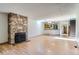 Open concept living room with stone fireplace, wood flooring, and view into the kitchen and staircase at 7476 E Arkansas Ave # 35-10, Denver, CO 80231