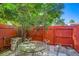 Cozy outdoor patio featuring a round glass table and four chairs surrounded by a red fence and lush greenery at 7476 E Arkansas Ave # 35-10, Denver, CO 80231