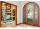 Elegant entryway featuring a wooden arched door, leading to a home office with built-in bookshelves at 6054 S Akron Way, Greenwood Village, CO 80111