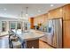 Bright kitchen with stainless steel refrigerator, light wood cabinets, and large island with pendant lights at 6054 S Akron Way, Greenwood Village, CO 80111